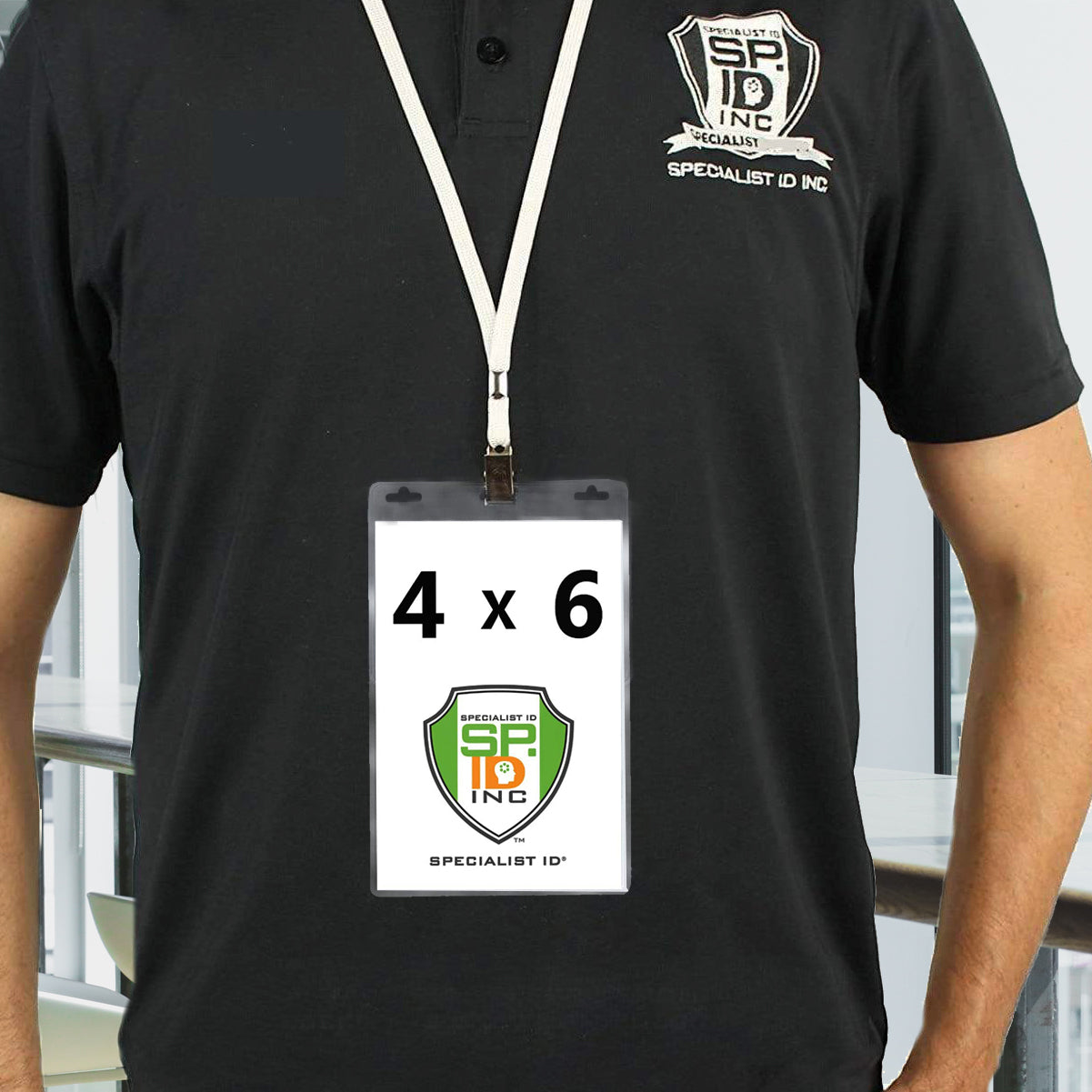 Person wearing a black polo shirt with "Specialist ID Inc" text and logo, displaying an oversized badge with a "4 x 6" label inside a Vertical Oversized 4X6 Vinyl ID Badge Holder (XL46V), also featuring the same logo.