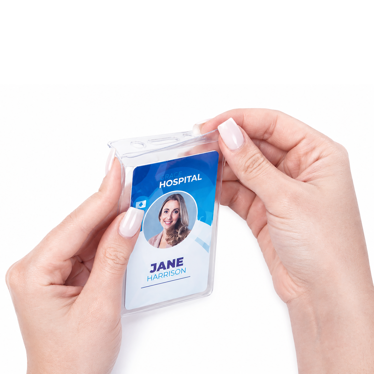 Close-up of hands holding a Vinyl Vertical Badge Holder with Flap (506-24FS) containing a hospital ID badge labeled "Jane Harrison" with photo, against a white background.