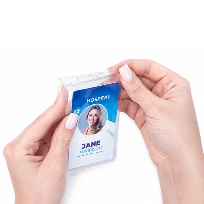Close-up of hands holding a Vinyl Vertical Badge Holder with Flap (506-24FS) containing a hospital ID badge labeled "Jane Harrison" with photo, against a white background.
