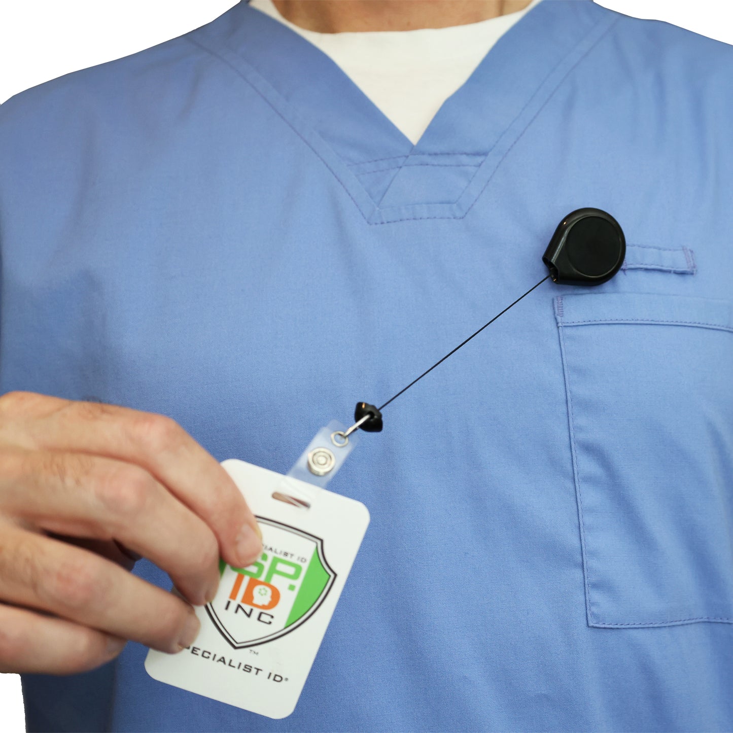 A person in blue scrubs holds an ID badge attached to a Premium No Twist Badge Reel with Swivel Spring Clip - Teardrop Shape (609-I-BLK) on their chest pocket.