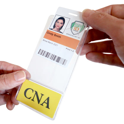 A hand is holding a durable composite material name badge with the name "Cindy Smith" and a photo. The badge includes a bar code, the job title "CNA," and the text "Since March 2021." This CNA BadgeBottom Badge Holder & Badge Buddy IN ONE!! - Vertical ID Badge Sleeve with Bottom Role Tag for Nurse Assistants ensures long-lasting use and clear professional identification.