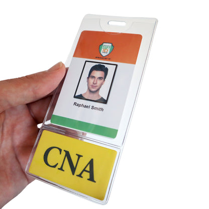 A hand holds a plastic ID card with the name "Raphael Smith" and a photo, secured in one of the durable composite material CNA BadgeBottom Badge Holder & Badge Buddy IN ONE!! - Vertical ID Badge Sleeve with Bottom Role Tag for Nurse Assistants, above a yellow tag displaying the letters "CNA".
