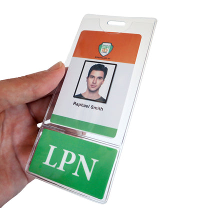 A hand holding an identification badge with a photo of a person, labeled "Raphael Smith" and the abbreviation "LPN" on a green background at the bottom. The ID badge holder features the LPN BadgeBottom Badge Holder & Badge Buddy IN ONE!! - Vertical ID Badge Sleeve with Bottom Role Tag for Nurses for displaying medical titles clearly.