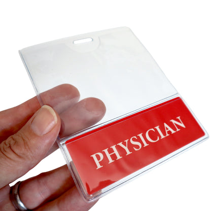 A hand holding a clear plastic ID badge holder with a red card inside that reads "PHYSICIAN" in white letters, perfectly showcasing the PHYSICIAN BadgeBottom Badge Holder & PHYSICIAN Badge Buddy IN ONE!! - Horizontal ID Badge Sleeve with Bottom Role Tag for Nurses.