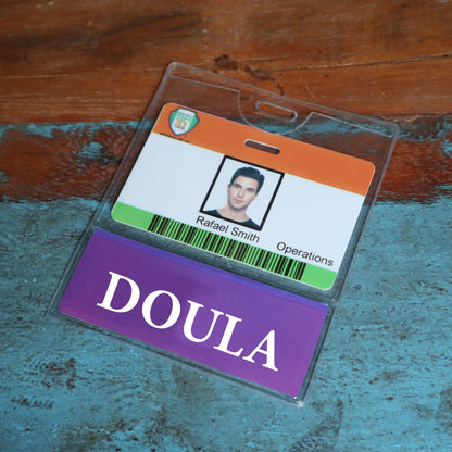 Rafael Smith's Operations ID badge on a wooden surface features the DOULA BadgeBottom—an integrated horizontal ID sleeve and role tag, highlighting clarity and organization. Sold by Specialist ID.