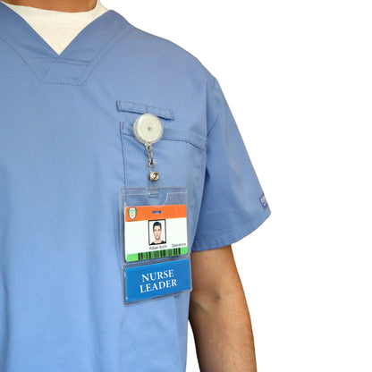 A person in blue scrubs displays the NURSE LEADER BadgeBottom Badge Holder & Badge Buddy, featuring a photo ID in a horizontal sleeve with a bottom role tag for Nurse Leaders, against an isolated white background.