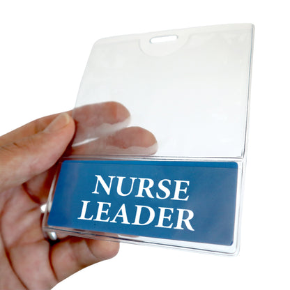 A hand holds a clear NURSE LEADER BadgeBottom ID holder featuring a blue card with "NURSE LEADER" text. Sold by Specialist ID.
