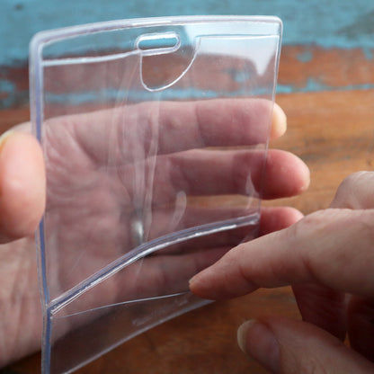 A person holding a clear, empty Premium Vinyl Horizontal BadgeBottom with Slot - Holder Only. This Premium Vinyl Horizontal BadgeBottom with Slot - Holder Only is perfect for showcasing your ID badge display effectively.