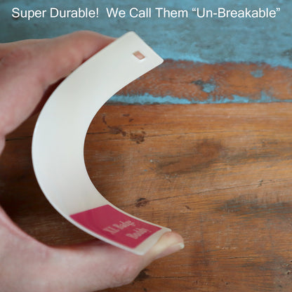 A hand bending a flexible plastic card resembling the Extra Large Doctor Badge Buddy, labeled "Un-Breakable," against a wooden surface. Sold by Specialist ID.