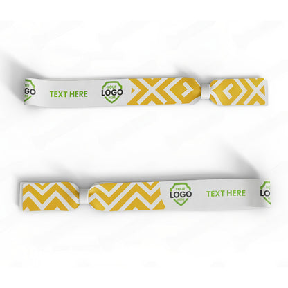 Custom Printed Wristband: Set of two white fabric wristbands with yellow geometric patterns, green hexagonal logo area, and customizable text space. Ideal as event wristbands with full-color dye-sublimation.