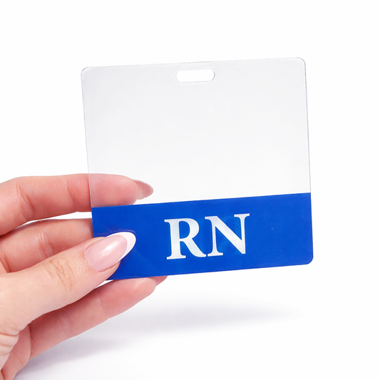 A hand holding a clear identification badge holder with a blue section at the bottom displaying the letters "RN". The Clear RN Badge Buddy - Horizontal ID Badge Backer for Nurses - Double Sided Print adds an extra layer of professionalism, making it easy to identify registered nurses.