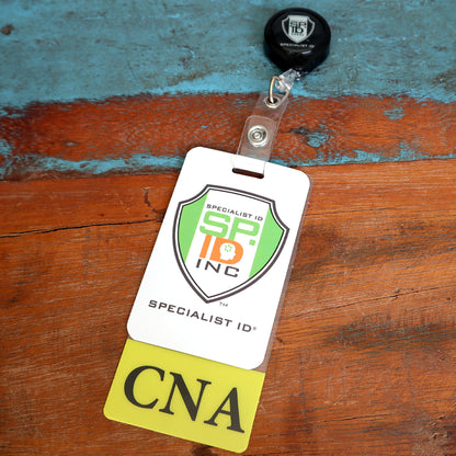 A Clear CNA Badge Buddy Vertical with Yellow Border for Nursing Assistants with a retractable holder and a yellow tag labeled "CNA" is attached to a wooden surface with a blue and brown background.