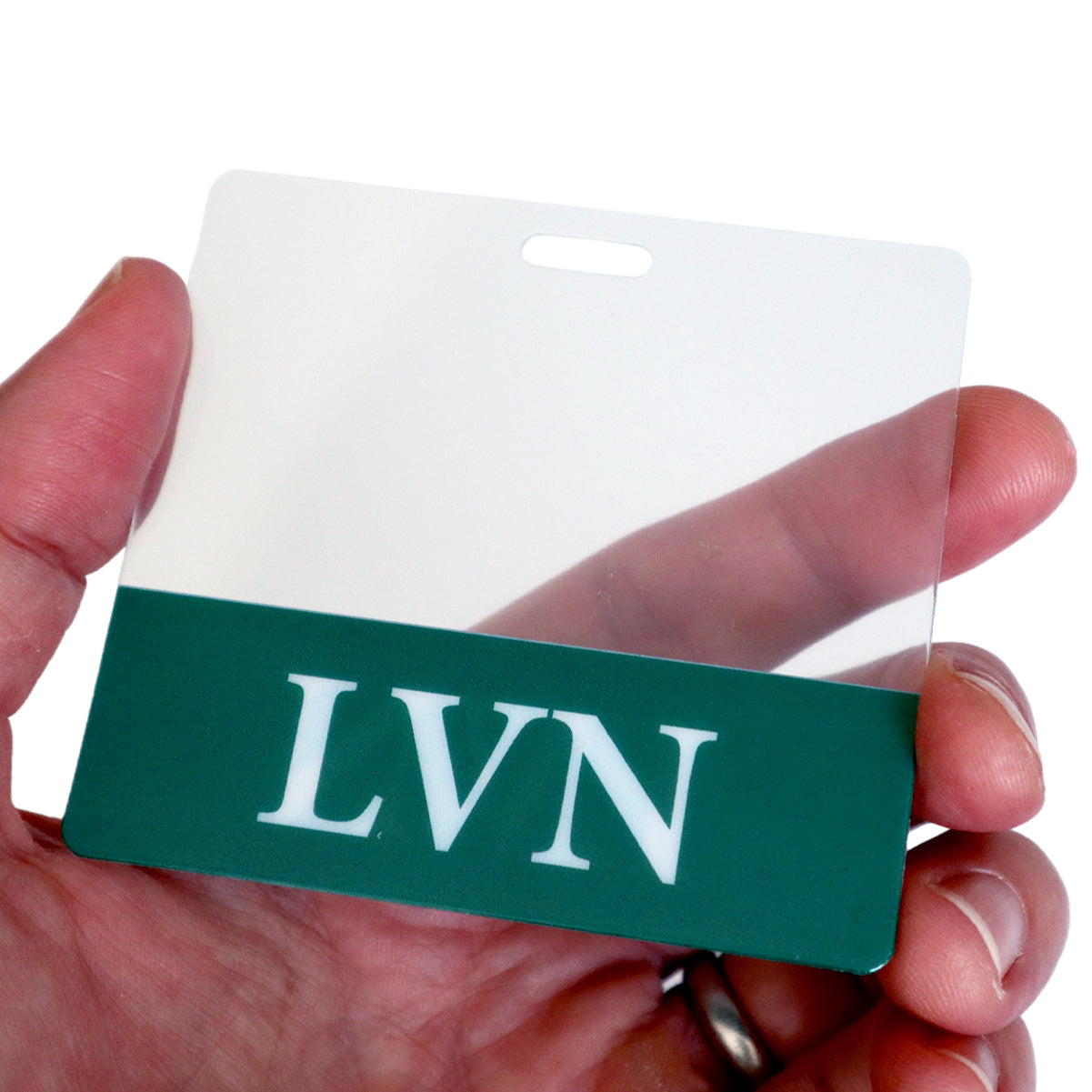 Hand holding a blank name badge with a green stripe at the bottom featuring the letters "LVN", acting as a perfect Clear LVN Badge Buddy - Horizontal ID Badge Backer for Licensed Vocational Nurses - Double Sided Print.