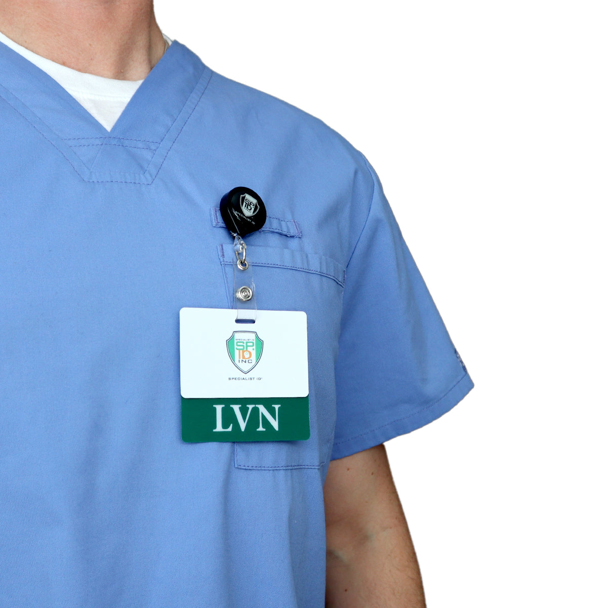 A person wearing blue scrubs with a white undershirt has a badge labeled "Clear LVN Badge Buddy - Horizontal ID Badge Backer for Licensed Vocational Nurses - Double Sided Print" attached to a retractable nurse badge holder near their chest pocket.