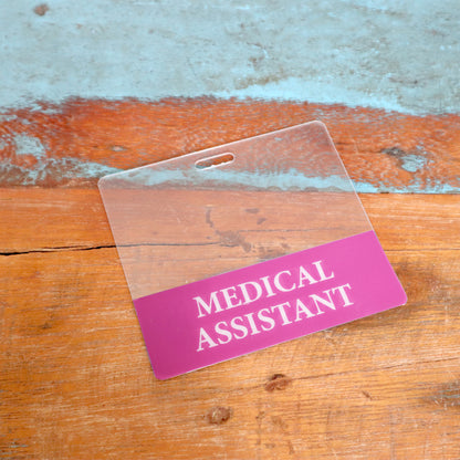 The Clear MEDICAL ASSISTANT Badge Buddy is a horizontal, double-sided nurse ID badge backer that enhances healthcare role recognition. It features "Medical Assistant" clearly for easy identification.