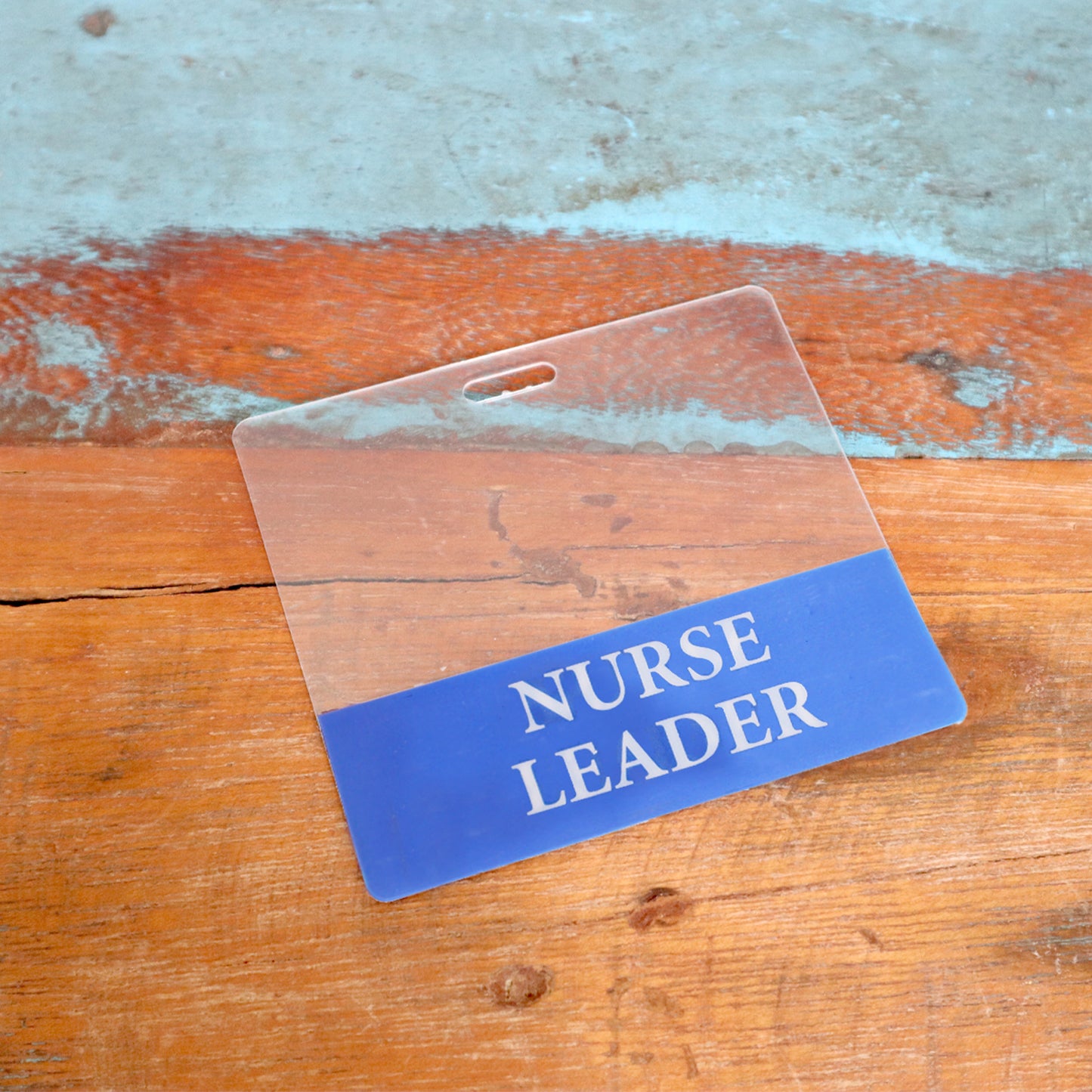 A Clear NURSE LEADER Badge Buddy (horizontal, double-sided) ID badge backer is displayed on a wooden surface. Sold by Specialist ID.