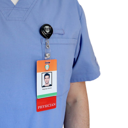 A person in blue scrubs wears a Clear PHYSICIAN Badge Buddy Vertical with Red Border for Physicians displaying an ID card that reads "Physician" and shows a photo and the name "Raphael Smith.