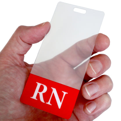 Close-up of a hand holding a Clear RN Badge Buddy Vertical with Color Border for Registered Nurses - Double Sided Print with a red bottom section displaying the white letters "RN," ideal for nurses who need a vertical ID backer.