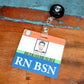 A Clear RN BSN Badge Buddy - Horizontal Nurse ID Badge Backer - Double Sided Print with a photo of Rafael Smith, labeled "RN BSN," attached to a retractable badge holder clip, is placed on a wooden surface.