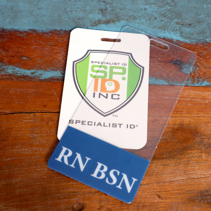 ID badge with SP ID INC logo, partially behind a clear plastic holder with a blue label that reads "RN BSN," on a wooden and painted surface, accompanied by a Clear RN BSN Badge Buddy Vertical with Blue Border for Nurses.