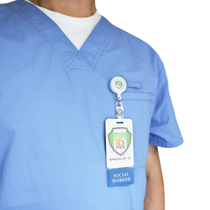 A person in light blue medical scrubs wears a Clear SOCIAL WORKER Badge Buddy Vertical with Blue Border for Social Workers, attached to a retractable badge holder on the chest pocket.