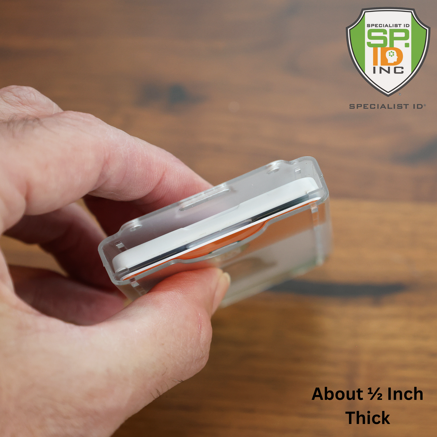 A hand holds the Dual Badge Holder Compatible with Centegix™ V2 Alarm Card + Standard ID Card, showing its approx. 1/2-inch thickness. The Specialist ID Inc. logo is visible in the upper right corner.