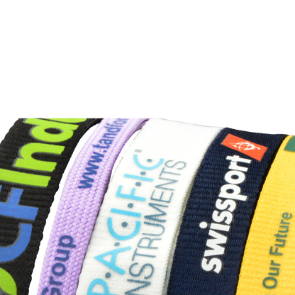 A close-up view of several colorful custom printed lanyards, each displaying different company logos and text in a variety of fonts and colors, showcasing the vibrant and personalized designs possible with Custom Printed Lanyards.