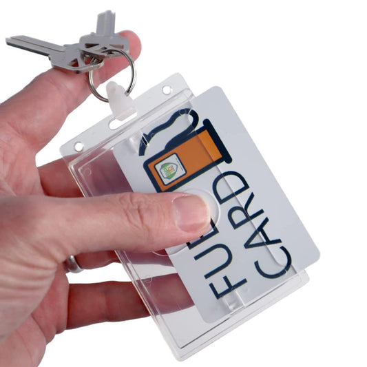 A hand holding a keyring with two keys and a clear plastic holder containing a Custom Rigid Fuel Card Holder with Key Ring - Customize by Adding Your Logo accessory for a fuel card.