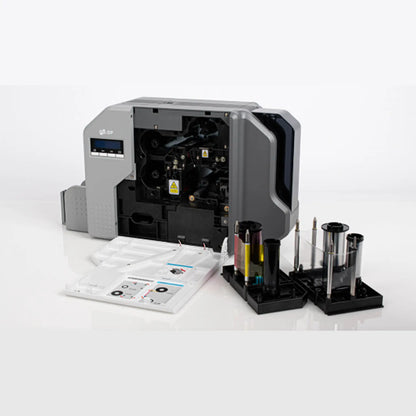 An IDP SMART-81S Single Sided Retransfer Card Printer P/N 653636 with visible internal components, positioned beside various toner cartridges and tools, set against a plain white background.