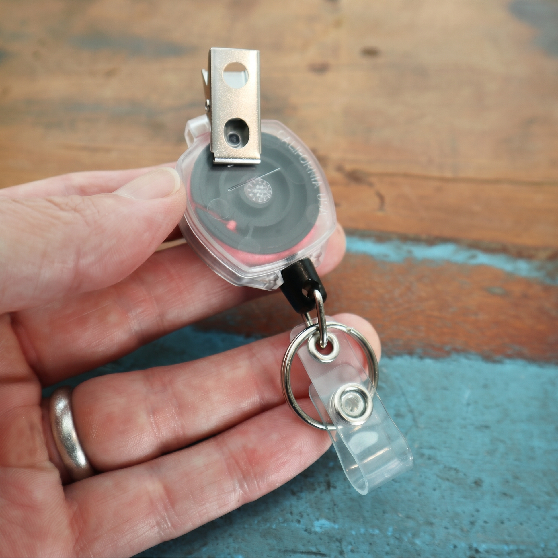 Hand holding pink cord KEY-BAK Sidekick badge reel with ID strap