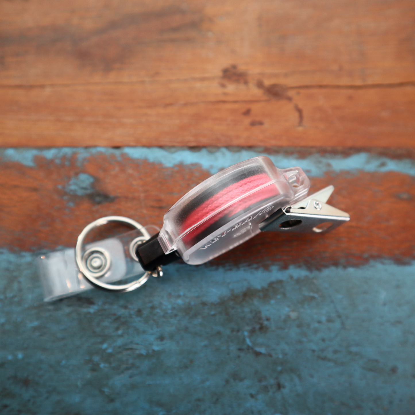 Pink cord KEY-BAK Sidekick badge reel on wood background