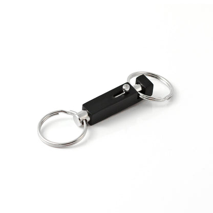 A black and silver Key-Bak #1101 Quick Release Pull-Apart Key Ring with two rings—one on each end—connected by a rectangular black block with a clasp mechanism, perfect for organizing separate vehicle and house keys.