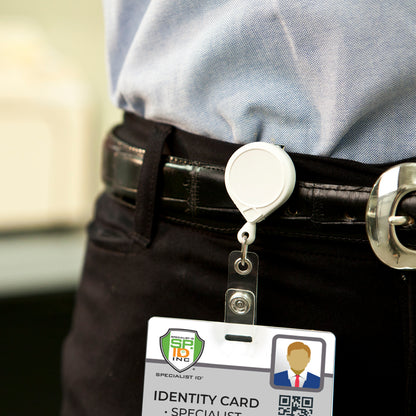 A person is wearing a retractable badge holder clipped to their belt, featuring a MINI-BAK #66 White Retractable Reel with 36” Nylon Cord, Vinyl ID Strap and Swivel Clip 0066-005 that securely holds an identity card.