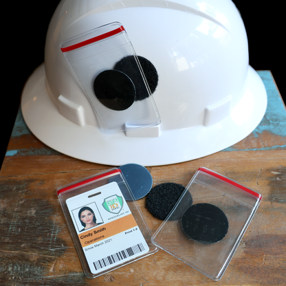 White hard hat with a Heavy Duty Resealable Badge Holder (PPP-1) and black adhesive hook & loop discs on wood. An ID card with a "PHX" logo is securely placed in the badge holder.