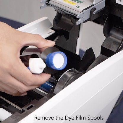 Person removing dye film spools from a printer with text 'Remove the Dye Film Spools'.