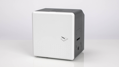 A small, gray and white electronic device with a minimalist design, the IDP SMART-81L Laminator Option for SMART-81 Printers (P/N 653635) features a front panel with a logo and minimal perforations, ensuring tamper-resistance.