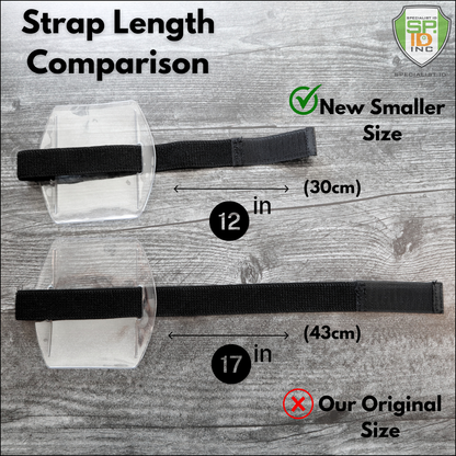 On a wooden surface, compare the adjustable hook and loop straps: a 12-inch one labeled "New Smaller Size" and a 17-inch one labeled "Our Original Size." These durable vinyl straps are designed for use with Vertical Armband ID Badge Holders (SPID-1710).