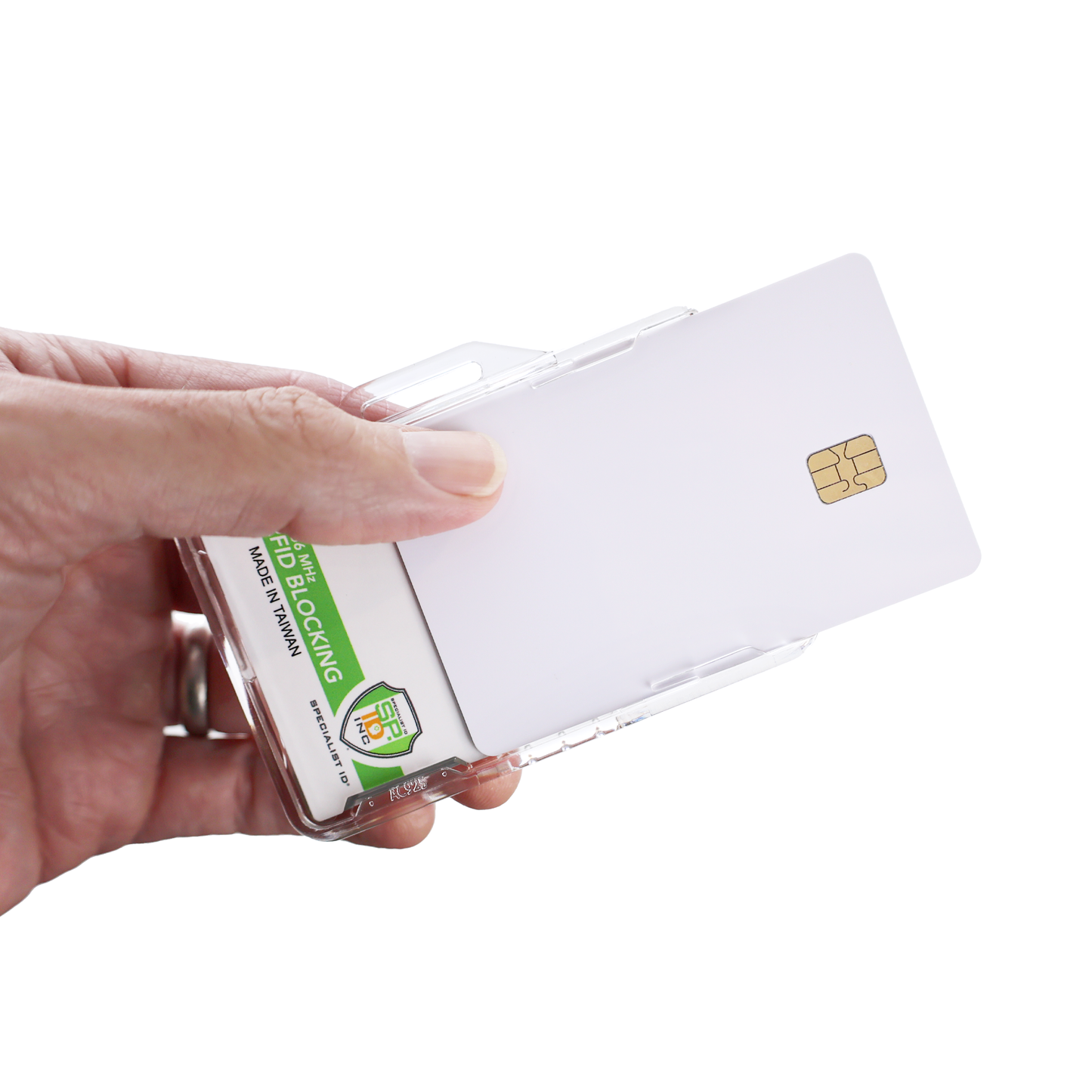 A hand holds the Specialist ID Dual Sided RFID Blocking Badge Holder (SPID-1760), a heavy-duty, transparent case for CAC, TWIC, PIV, HSPD-12 & Secure ID badges. It contains a white smart card with a gold chip and features an RFID blocking label.
