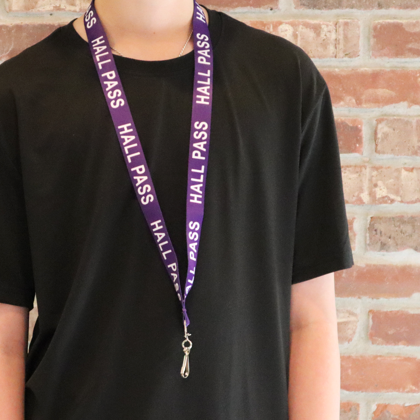 Person wearing a black t-shirt and a purple Hall Pass Lanyard - Safety Breakaway Lanyards with Swivel Hook (SPID-2190), standing in front of a brick wall.