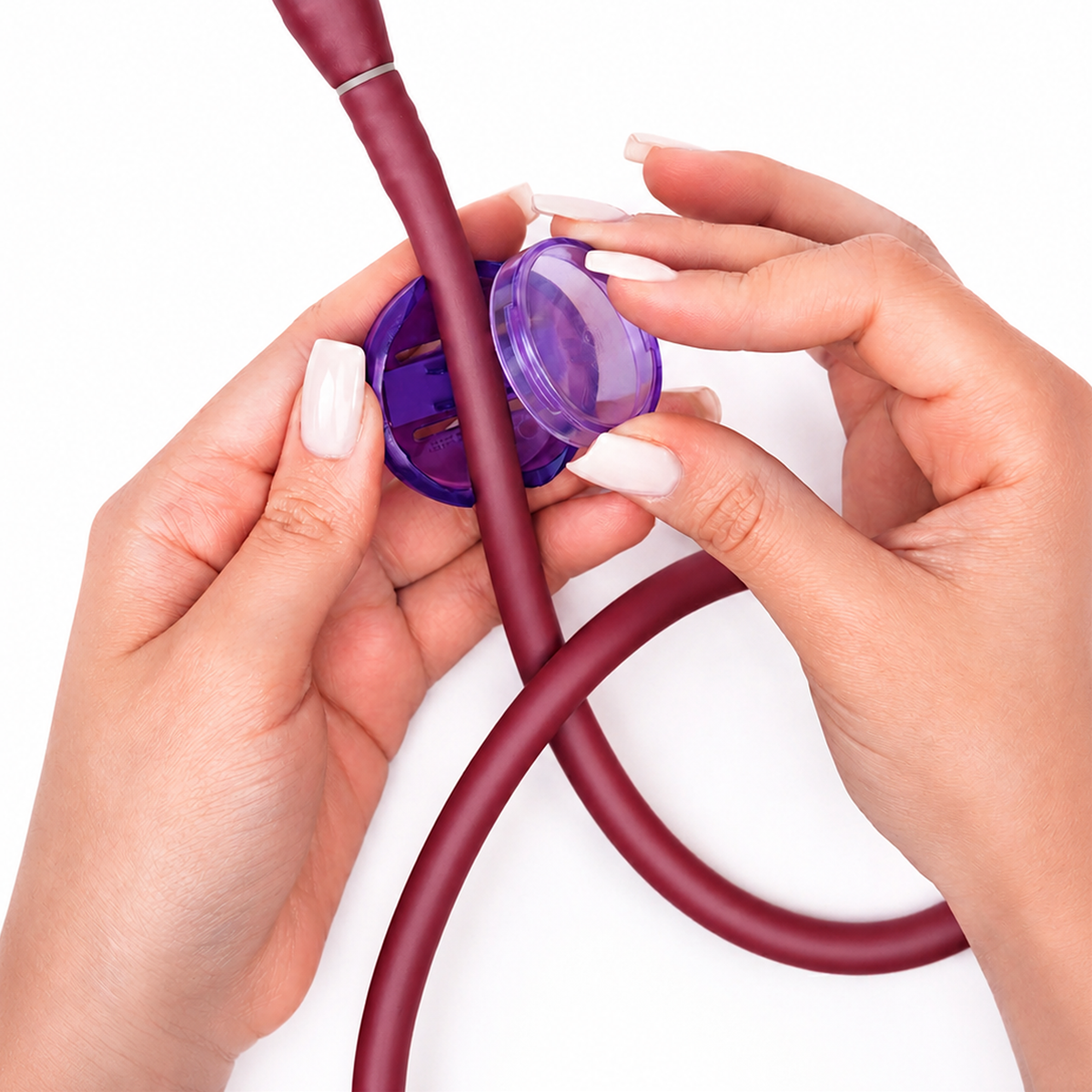 Hands holding a purple circular Stethoscope ID Tag Cover with Writable Surface (SPID-3820) attached to a maroon tube, against a white background—showcasing a customizable accessory designed for easy stethoscope identification.