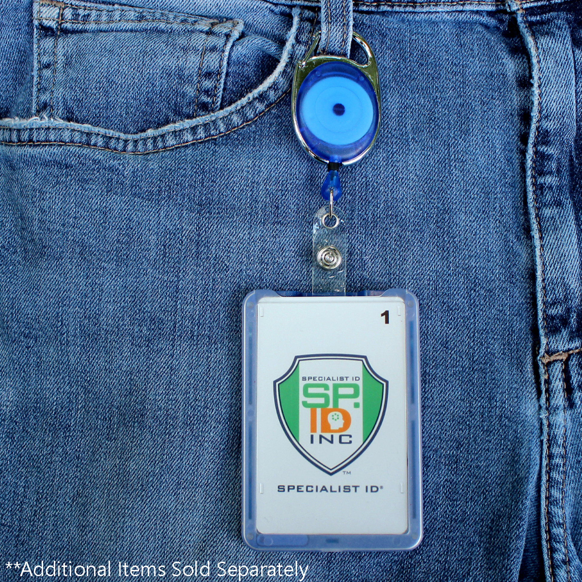A Premium Oval Badge Reel with Carabiner and Belt Clip (2120-71XX), featuring a blue evil eye charm, secures an ID badge with a Specialist ID logo to blue jeans; text at the bottom reads, “Additional Items Sold Separately.”.