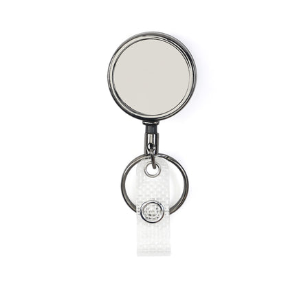 A polished gunmetal round metal retractable badge reel with a circular mirror face, attached to a split key ring and a clear plastic strap with a snap button.