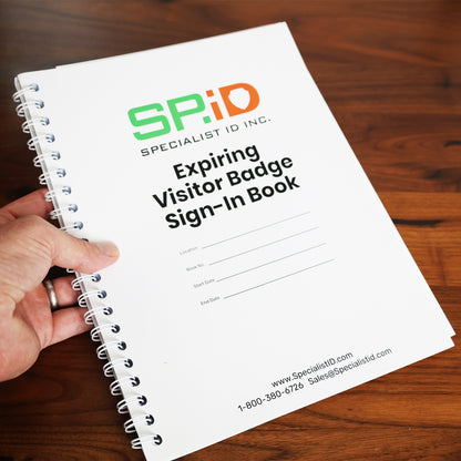 A hand holds the spiral-bound "Expiring Visitor Badge Stickers Log Book – One-Day Security Badges with Sign-In Records," featuring blank fields for location, date, and time on the cover. No SEO keywords are present in this description.