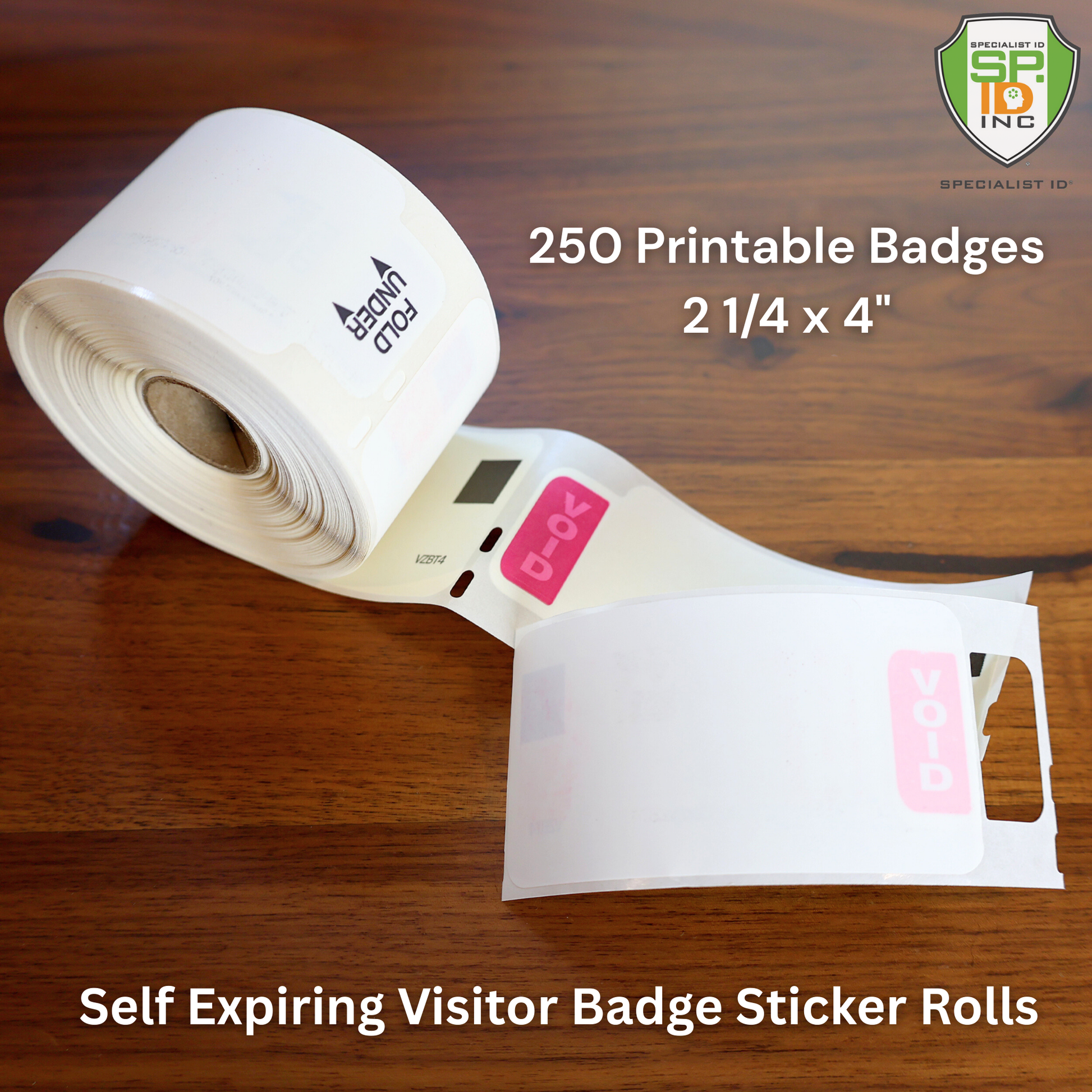 A roll of Printable Expiring Visitor Badge Roll Stickers for Thermal Printers (SPID-8340) showing "VOID" text on a wooden surface; includes 250 printable badges, each measuring 2 1/4 x 4 inches.