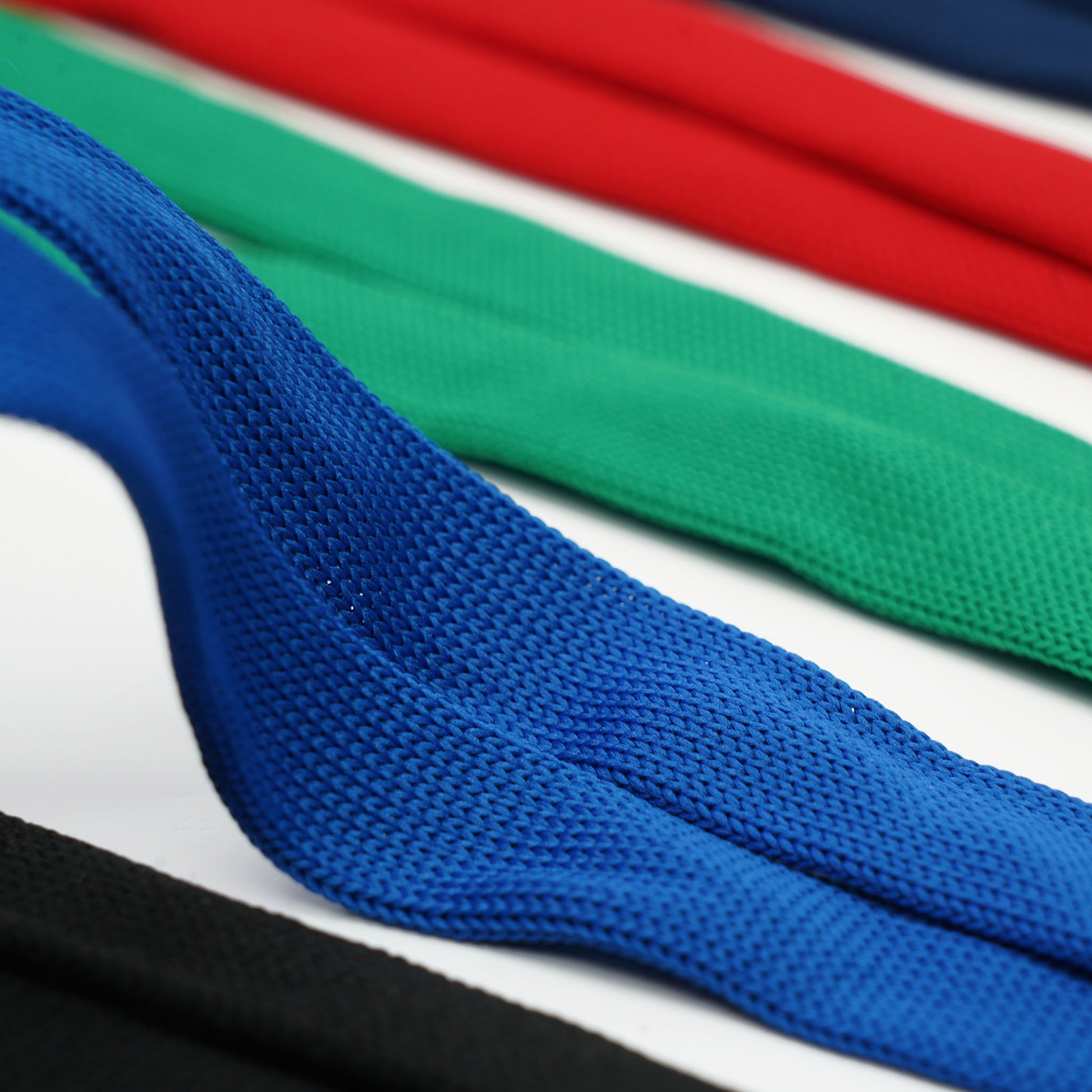 Close-up of textured fabric ribbons in blue, green, red, and black, laid out in parallel rows on a white background—perfect for crafting heavy duty Cruisin Through Life™ Retractable Badge Holders or stylish badge reel lanyards for your ID badge. Available in a convenient 5 Pack (Family Pack)—great for your cabin cards!.