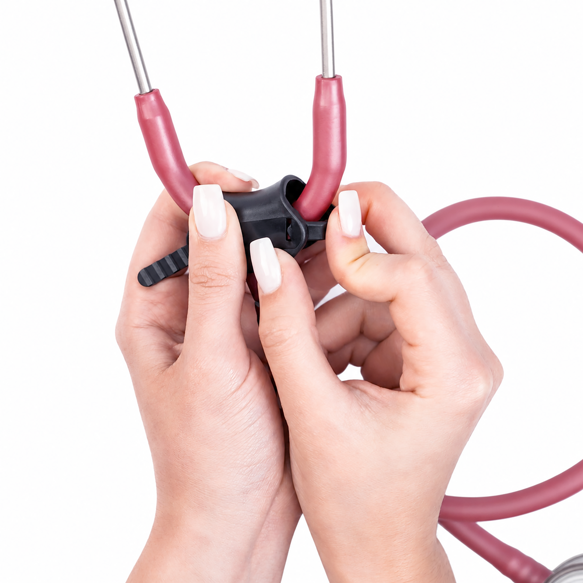 Close-up of a person's hands adjusting the plastic black stethoscop clamp of a stethoscope with a pink tubing and silver metal tubes on a white background.