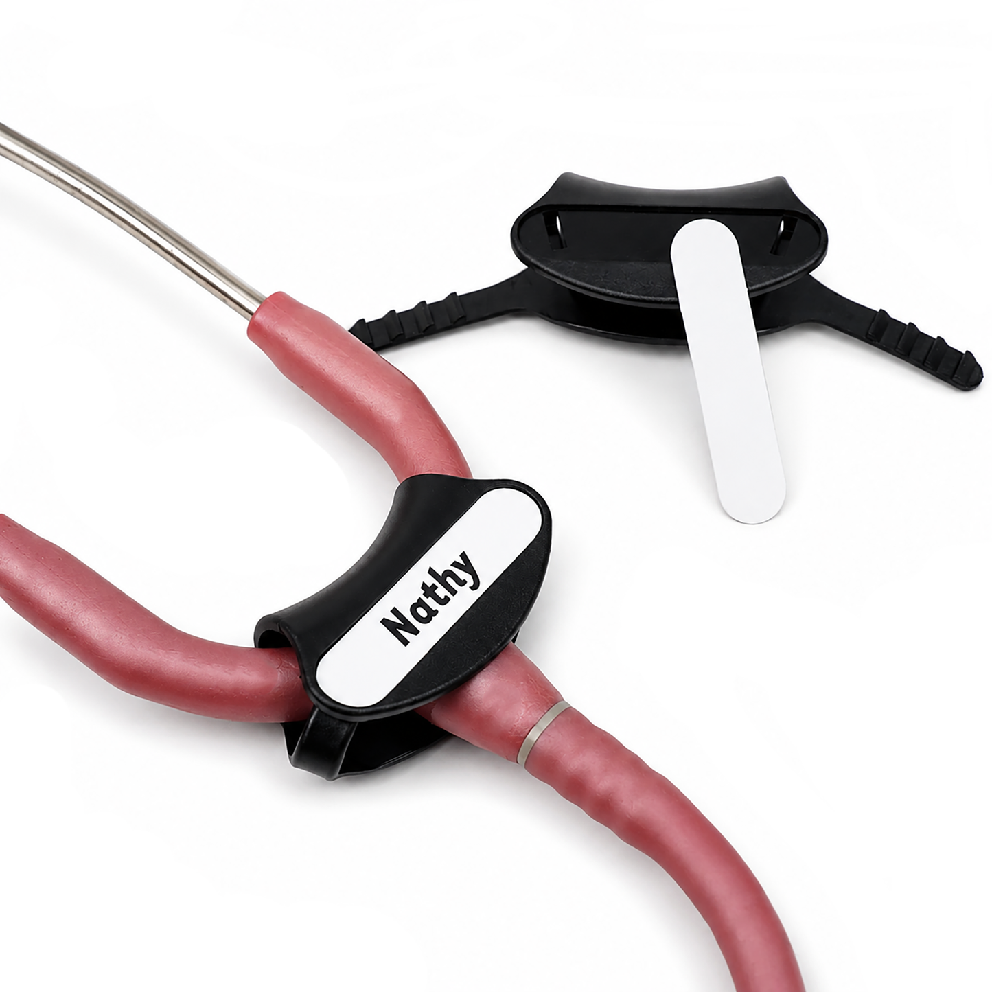 A close-up of a pink Littmann cardiology stethoscope with pink tubing and a black stethoscope plastic tag shown both separate and attached to the pink stethoscope with a custom write on nametag surface "Nathy" on a clean white background. (SPID-9760) Ideal for medical professionals.