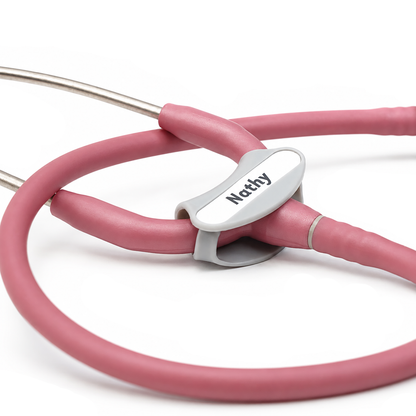 Close-up of a pink Littmann Cardiology stethoscope with a gray Yoke Stethoscope ID Tag - Blank with Write on Surface (Cardio & Cardiology Compatible) (SPID-9760) attached to the tubing, ideal for medical professionals. featuring a custom nameplate engraved with 'Nathy'.