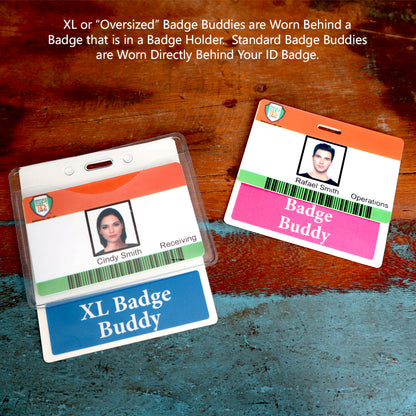 Two ID badges with photo IDs are displayed on a wooden surface. One badge reads "Cindy Smith - Receiving" with an Oversized Fully Customizable Badge Buddy Horizontal XL- (Extra Large Size) underneath, and the other reads "Rafael Smith - Operations" with a standard Custom Printed Badge Buddy.