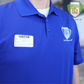 A person wearing a blue polo shirt with the Specialist ID logo and an Expiring Visitor Badge Stickers Log Book one-day security badge labeled “Mike” stands in front of the Specialist ID company logo.
